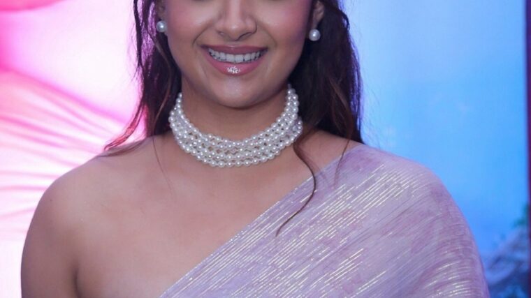Keerthy Suresh smiling at a film event in a lavender saree