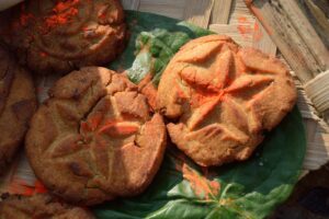 Golden thekua with pressed patterns on a leaf, prepared for Chhath Puja
